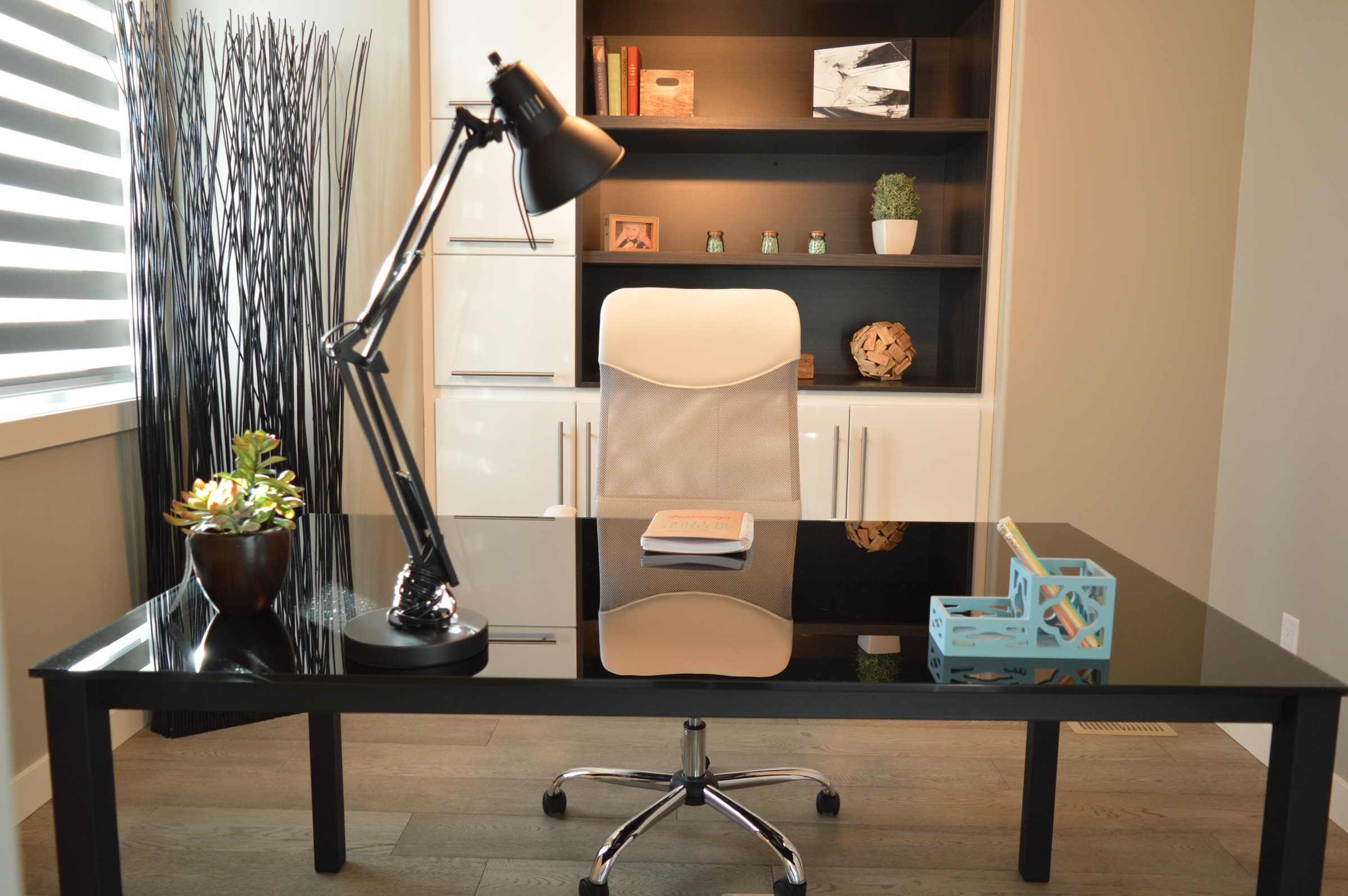 An organized home office desk with a bookshelf, desk organizer, and clear work surface