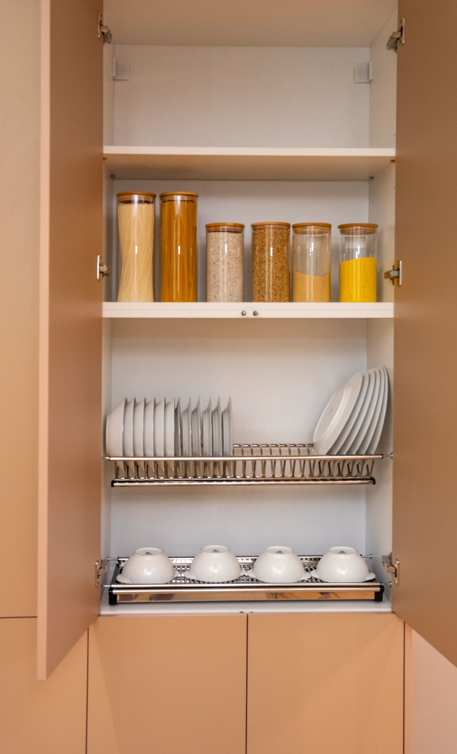 An organized kitchen cabinet with dishes arranged on a dish rack, part of Kim Nelson's kitchen and closets project
