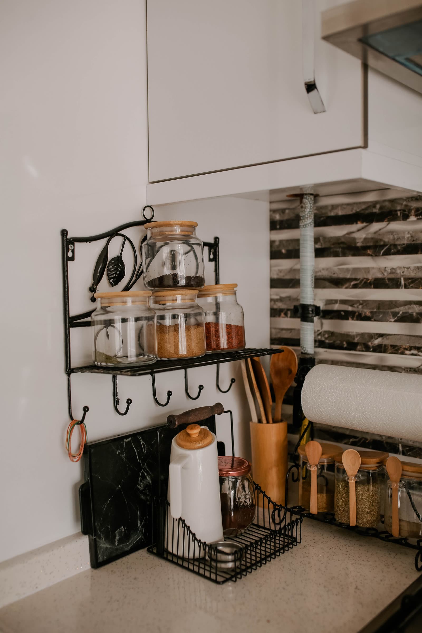 An organized wall shelf with labeled spice jars above a kitchen counter