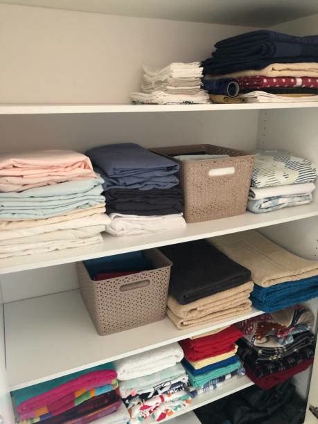 A linen closet with folded sheets and towels organized by shelf