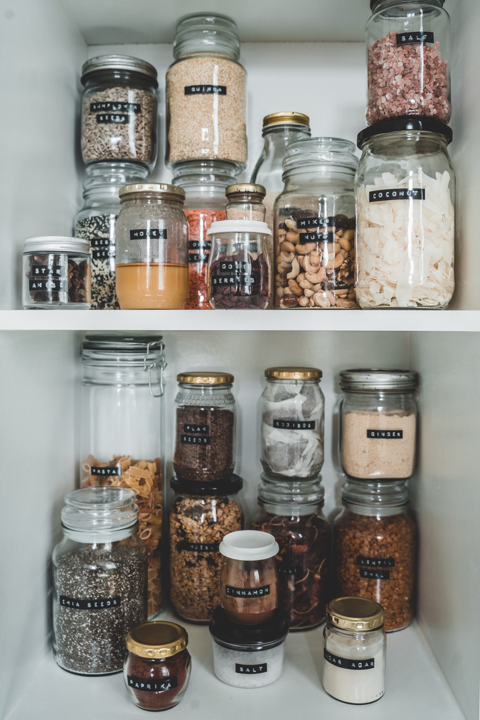 Labeled glass jars of pantry staples arranged on organized shelving
