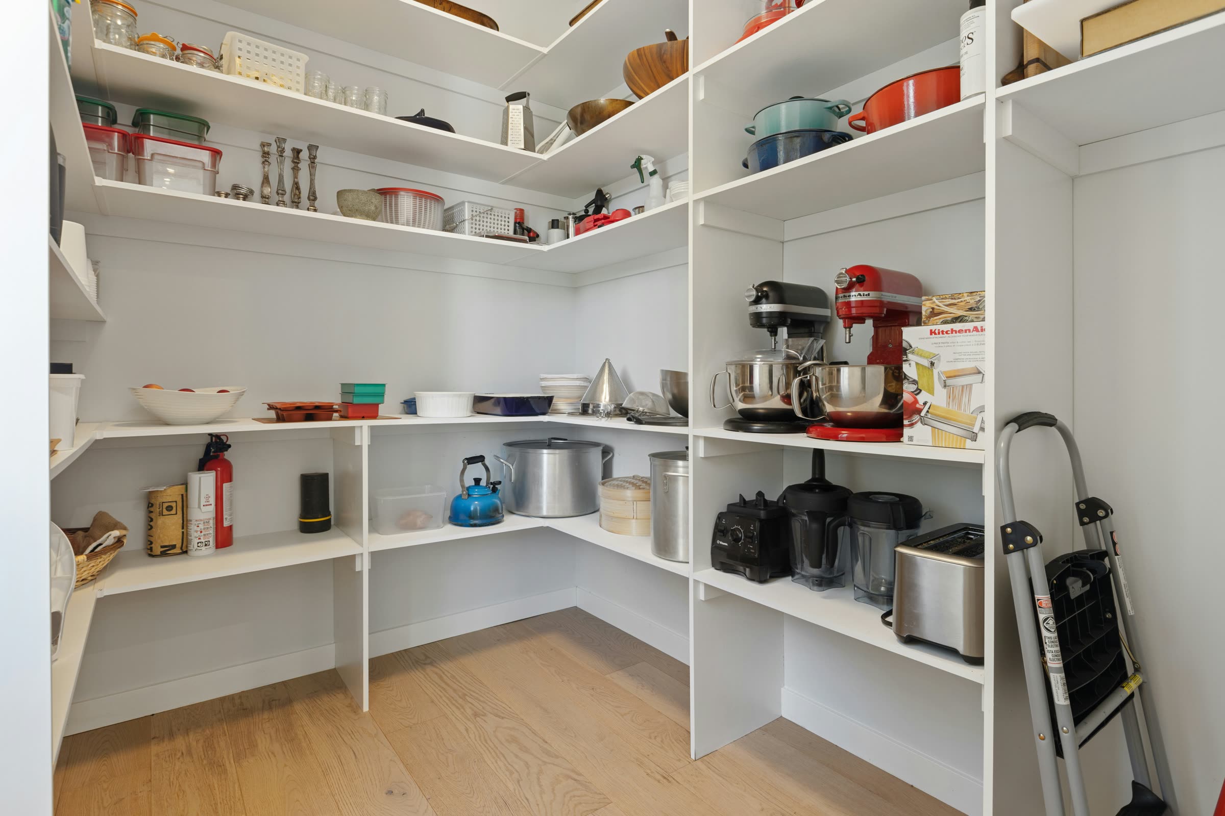A comprehensive organized pantry with labeled shelving for cookware, appliances, and pantry staples