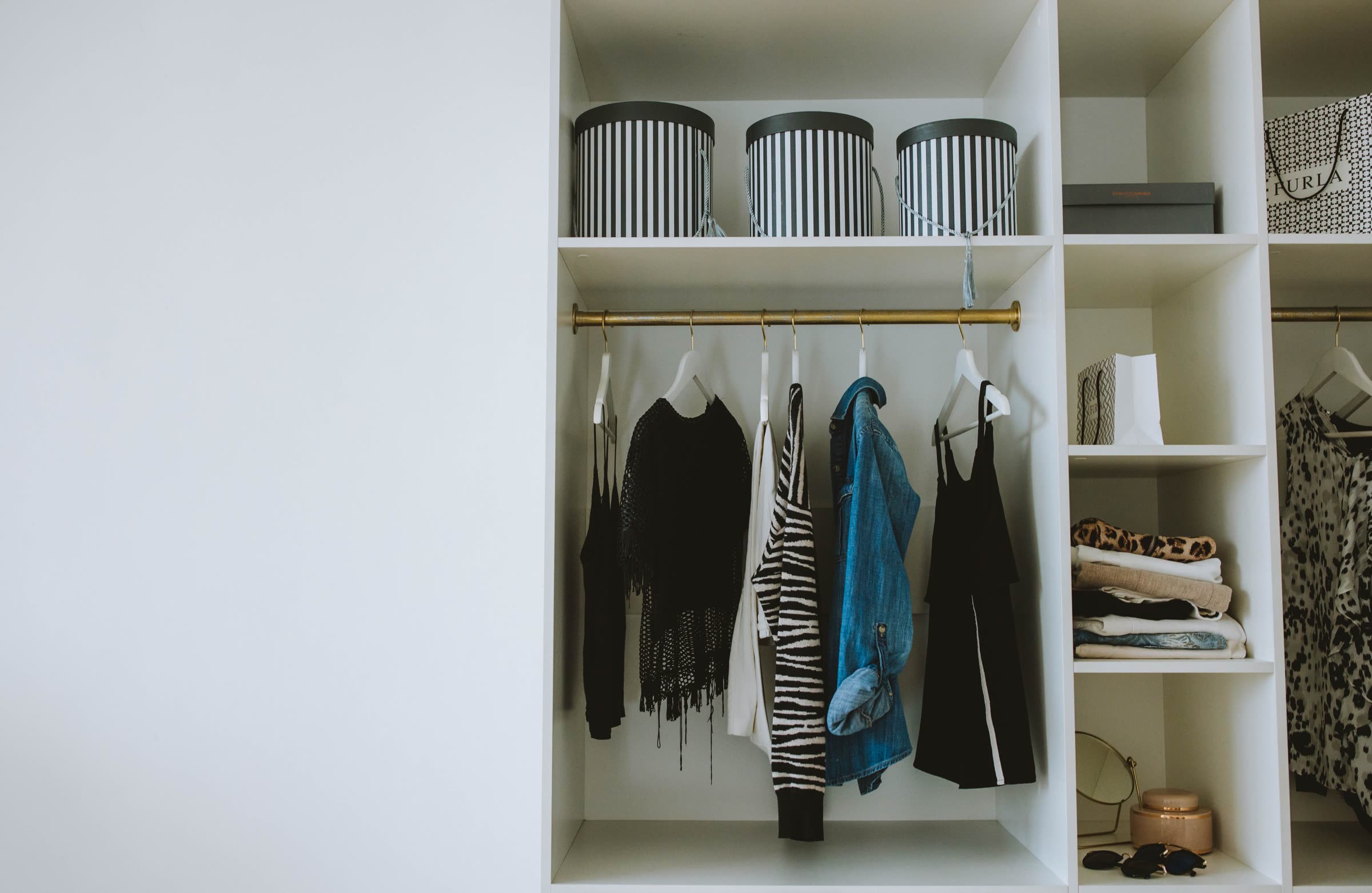 Closet shelving with hat boxes and neatly hung clothing