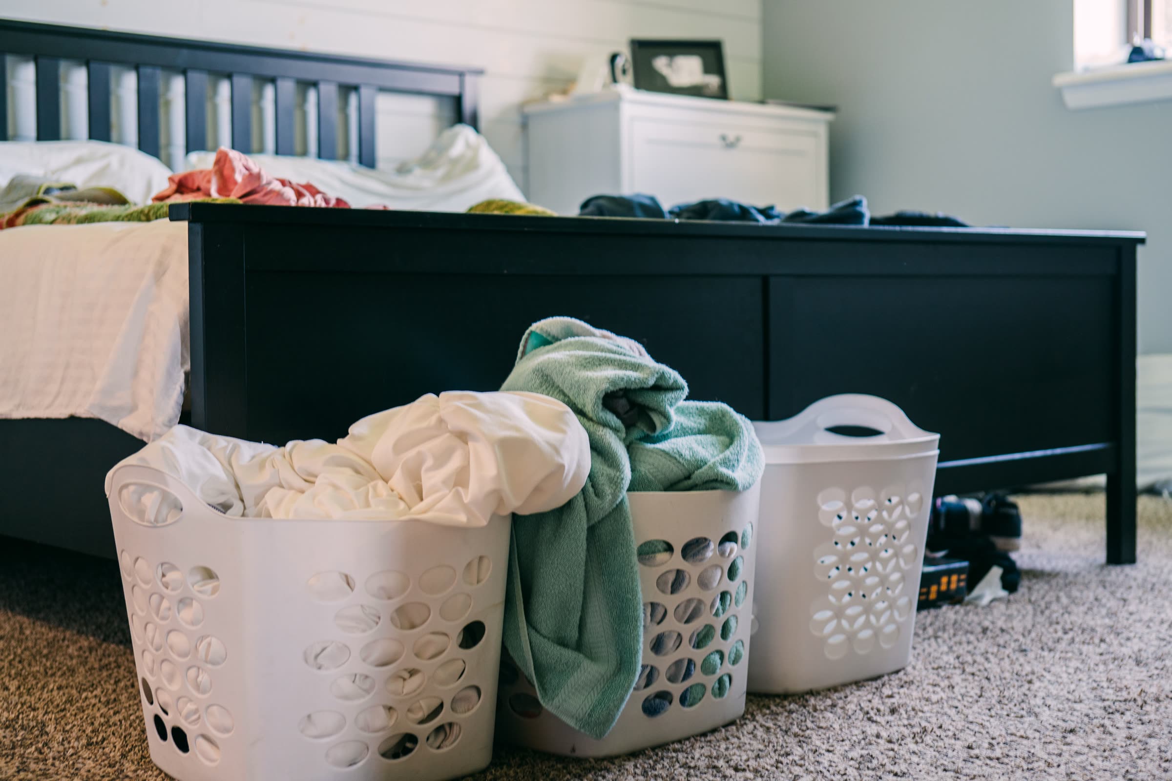 Laundry baskets filled with towels and linens in a bedroom