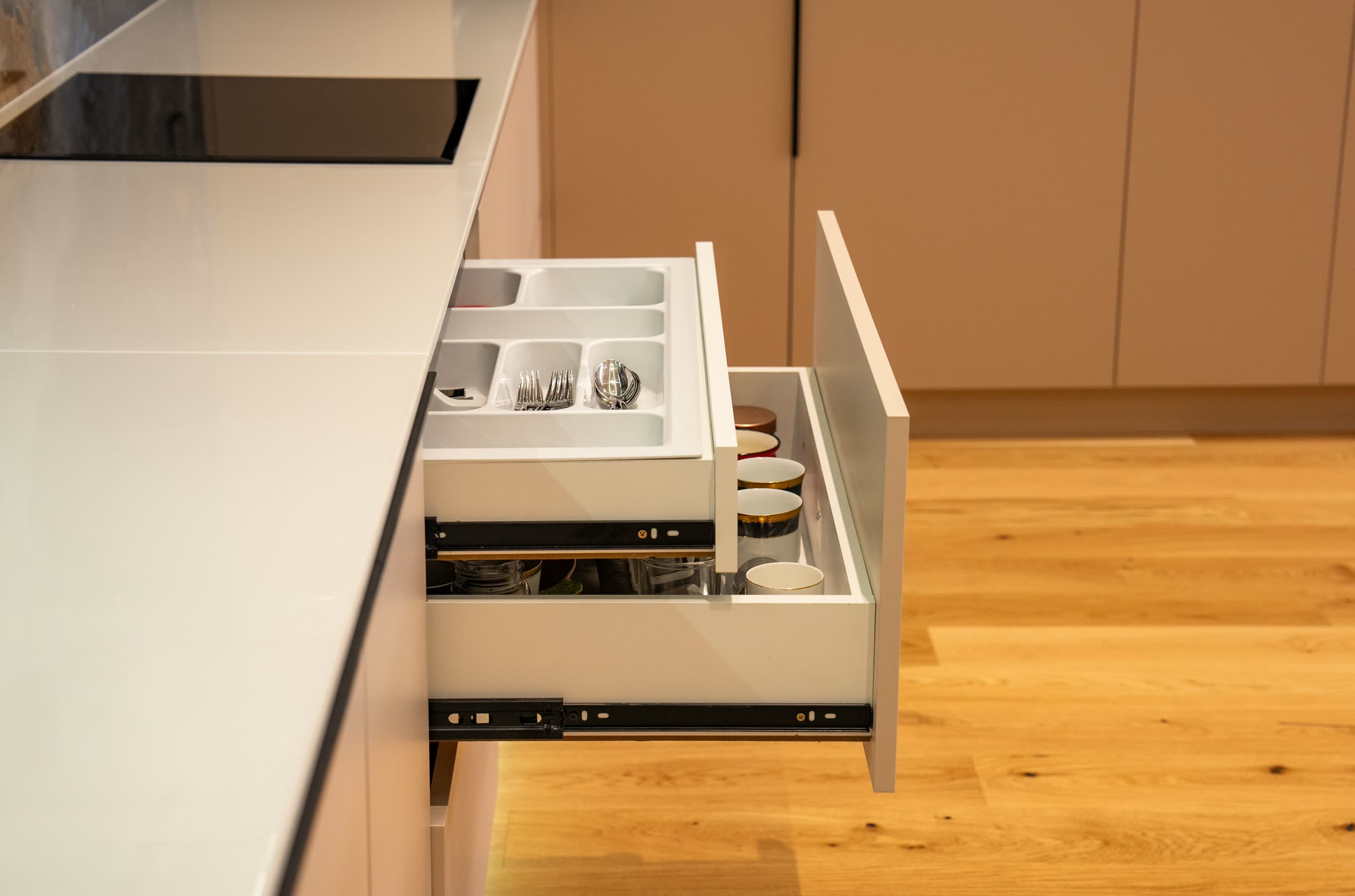 An organized kitchen drawer with utensils and glassware in place